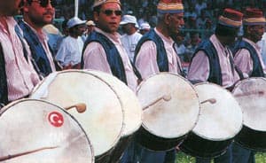 Alt Mannen in traditionele kledij die op trommels slaan